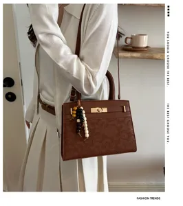 Vista detallada del bolso de mano retro marrón en cuero con elegante abalorio de perlas.