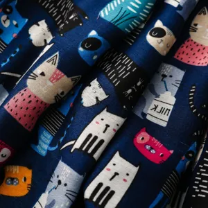 Nahaufnahme des Stoffes mit süßem Cartoon-Katzenmuster, weiche Textur, dunkelblaue Farbe.