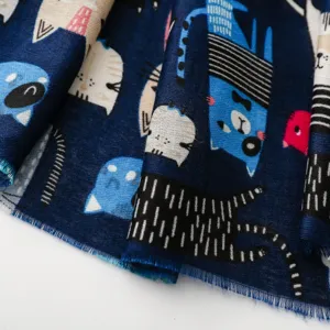 Nahaufnahme Detail eines dunkelblauen Baumwollschals mit niedlichen bunten Katzen Muster Fransen.