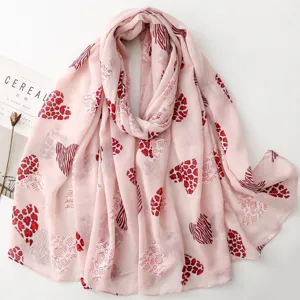 Vista detallada de un pañuelo rosa claro con corazones rojos y estampado animal.