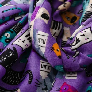 Nahaufnahme eines lila Schals mit niedlichem Katzenmotiv, weiche Stofftextur und klare Details.