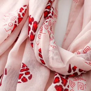 Detalle de bufanda rosa claro con estampado de leopardo rojo y formas geométricas abstractas.