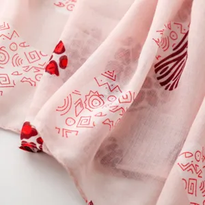 Primer plano detallado del pañuelo rosa ligero con motivos geometricos y animales rojos.