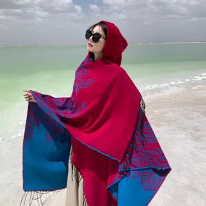 Ethnic style hooded cloak shawl with vibrant red and blue color blocking, tassel hem, detail view.