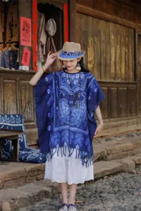 Λεπτομερής όψη έθνικ μπλε tie-dye print κάπας σάλι που φοριέται σε παραδοσιακό δρόμο.