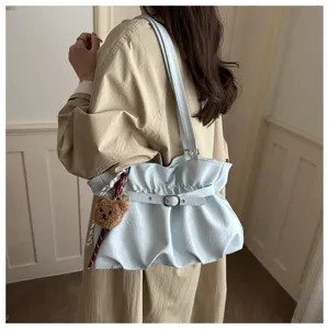 Vista detallada del elegante bolso de hombro azul claro plisado con bonito colgante de oso.