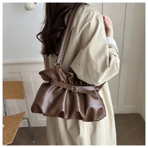 Vista detallada del bolso de hombro plisado marrón con hebilla, estilo retro elegante y chic.