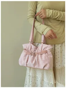 Primo piano dettagliato che mostra la borsa a tracolla rosa a pois con cinturino in pelle.