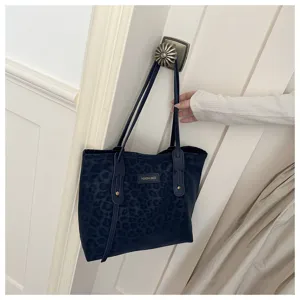 Detailed shot of dark blue leopard print tote bag hanging on door, showcasing texture and handle.