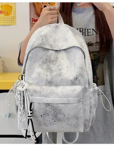 Dettagli dell'elegante zaino con stampa stelle tie-dye e ciondolo in pizzo per la scuola.