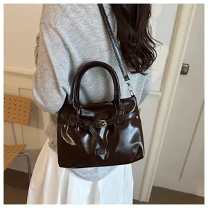 Dark brown glossy leather handbag featuring a stylish belt buckle design and crossbody strap.