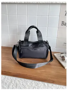 Primer plano del bolso cilíndrico de nailon negro que muestra tela duradera y asas resistentes.