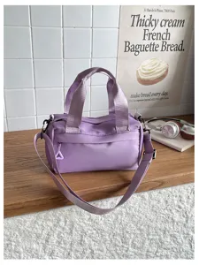 Vista detallada del elegante bolso de hombro de nailon morado en un estante de madera.