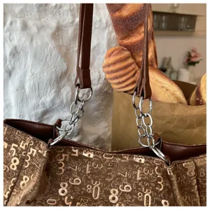 Detail of large capacity brown tote bag with metallic number print and chain strap for women.