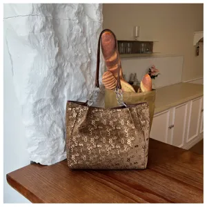 Detail shot of brown metallic tote bag with numeric print, shoulder chain straps, lifestyle setting.