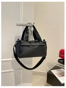 Vista detallada de un bolso cruzado negro de nylon versátil colgado en una puerta con cremallera fuerte.
