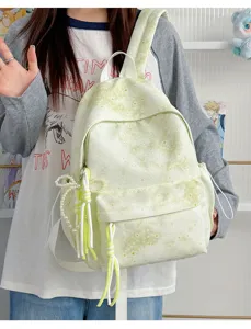 Dettaglio dello zaino scolastico verde tie-dye con grazioso fiocco di perle e nappa pendente.