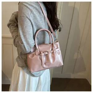 Pink glossy leather handbag detail showing retro belt buckle and strap in daily scene.