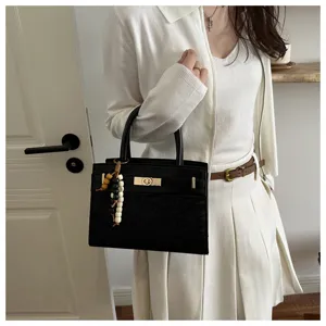 Elegante bolso de mano estructurado negro para mujer con asa y detalle de metal.