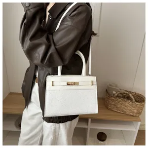 Primer plano del elegante bolso blanco con panel inferior texturado y cierre dorado elegante.