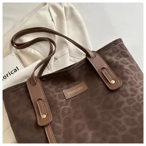 Brown leopard print tote bag detail showing structured leather handle and decorative branded patch.