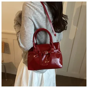 Red patent leather handbag with retro belt design, stylish shoulder and crossbody bag for women.