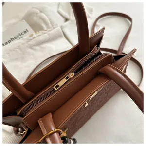 Bolso bandolera vintage marrón estructurado con asas y elegante patrón de monograma para mujeres.