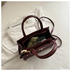 Detalle de estilo bolso estructurado burdeos, vista de bolso con asa, elegante bolso cruzado.