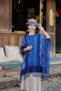 Λεπτομέρεια μπλε έθνικ κάπας tie-dye με ρετρό μοτίβο και κρόσσια σε ρουστίκ σκηνικό περιβάλλον.
