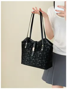 Zwarte shopper tas detail met cijferprint, metalen sluiting en dubbele schouderbanden.