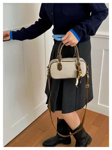 Pequeño bolso bandolera de lona con ribete de cuero marrón y abalorio de cuentas.