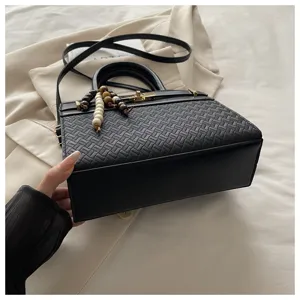 Zwarte geweven schoudertas voor dames, elegante handtas voor werk metGouden hardware details.