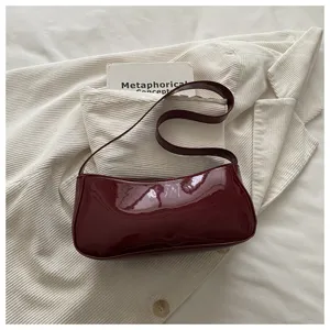 Burgundy patent leather baguette bag detail, stylish retro shoulder bag closeup view.