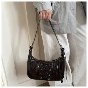 Vue détaillée du sac porté épaule en cuir verni marron foncé avec laçage chic à l'avant.
