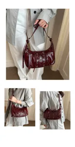 Gros plan sur le sac hobo en cuir vernis bordeaux avec laçage frontal et œillets métalliques.