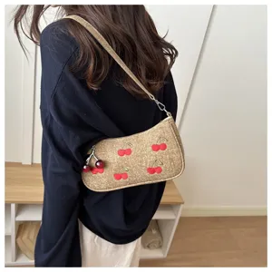 Detail view of the cherry embroidered vintage shoulder bag with cute pendant, elegant style.