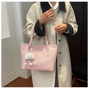Detalle cercano del bolso tote rosa elegante para viajero con colgante de nube de peluche.
