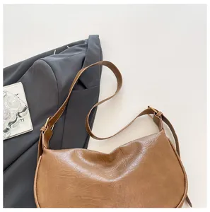 Dettaglio borsa a tracolla marrone in pelle PU retrò, classica forma a sacco con cinturino sottile.