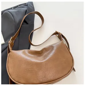 Primo piano di una borsa a tracolla marrone vintage a mezzaluna con cinturino regolabile.