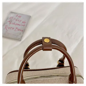 Bolso de mano minimalista elegante, vista detallada con asas de cuero marrón y cremallera.