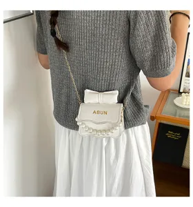Sac bandoulière mini blanc chic pour femme, avec nœud mignon et chaîne en perles.