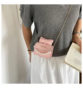 Vue de détail rapprochée du mini sac bandoulière rose avec nœud et chaîne de perles.