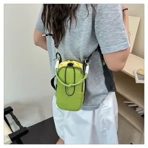 Nahaufnahme Detail der gruen gelben Kontrast Handytasche mit Riemen im Szene Stil.