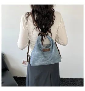 Vista di dettaglio dello zaino e della borsa in tela denim retro con cinturini in pelle marrone.