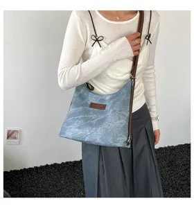 Dettaglio borsa a spalla retrò casual, tessuto denim vintage con cinturino marrone.