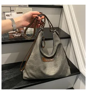 Vista dettagliata dello zaino e della borsa casual in tela grigia con manici in pelle.