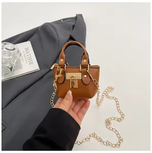 Primer plano detallado de un mini bolso de cuero marrón con elegante herraje dorado.