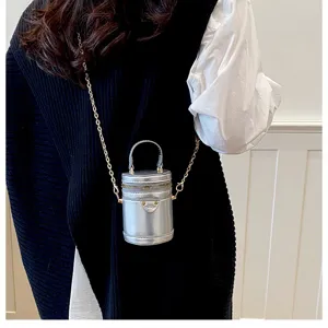 Détail de sac bandoulière cylindrique argenté montrant une bandoulière chaîne et un design.