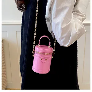 Gros plan détaillé sur le sac à bandoulière cylindrique rose élégant avec chaîne dorée.
