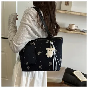 Primo piano della borsa nera con stampa di farfalle e grazioso portachiavi a forma di orsetto.